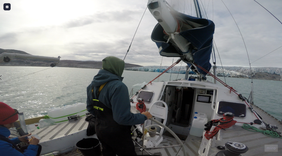 Helming the research vessel in a Greenland fjord